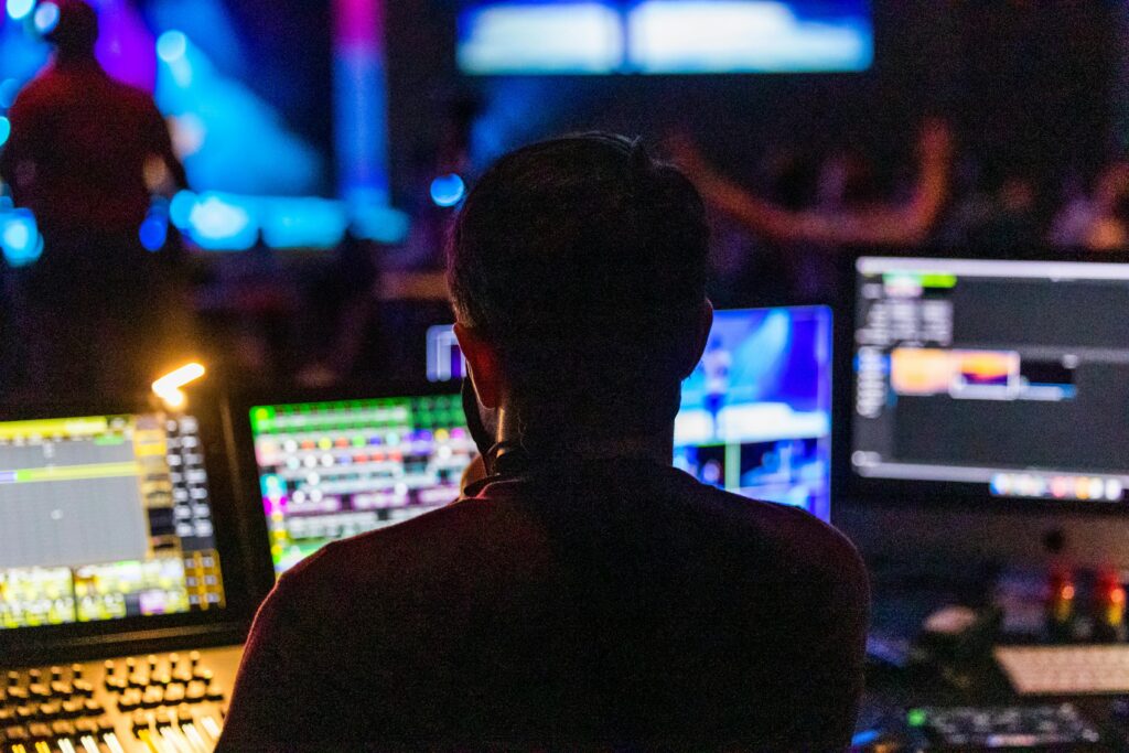 Event producer from behind at the control panel with multiple screens during a live show.